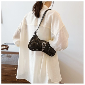 Detail of a black PU leather underarm bag with silver studs and vintage metal buckles