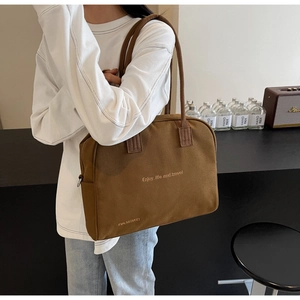 Close-up of brown canvas tote bag featuring Enjoy Life and Travel gold typography