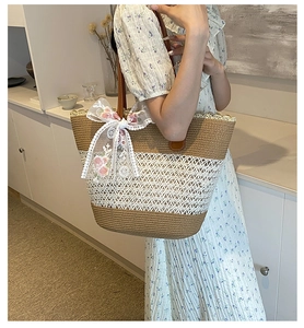 Detail of woven straw tote bag featuring white floral lace ribbons and brown leather straps