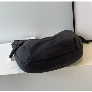 Detail of minimalist black nylon crossbody bag with unique chunky woven rope zipper pull