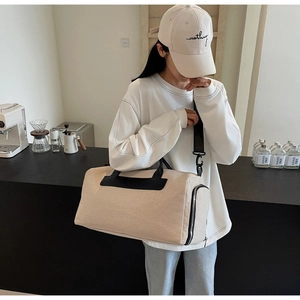Detailed view of beige canvas crossbody bag with black leather trim and nylon strap