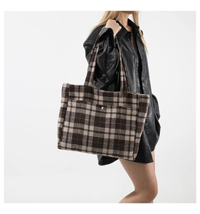 Gros plan d'un grand sac cabas en laine à carreaux avec poche avant et boucle métallique