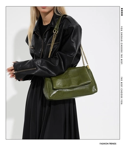 Fashionable green PU leather shoulder bag with gold chain strap on a model