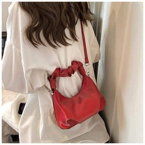 Close-up of red PU leather bag with pleated cloud handle and metallic zipper detail