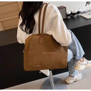 Detailed close-up of a large caramel canvas tote bag featuring Enjoy Life travel text