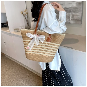 Straw tote bag with white lace bow and floral patterns worn by a model in soft light