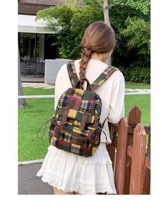 Detail view of plaid tweed backpack with multicolored woven fabric and decorative buckle strap