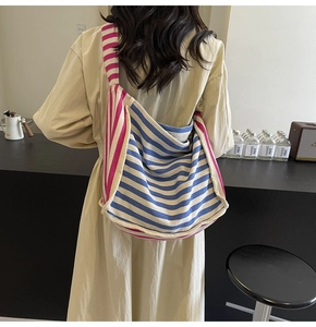 Close-up of a large canvas tote bag with blue and pink stripes on a female model