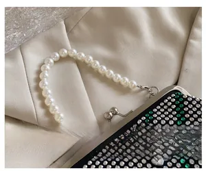 Close-up of rhinestone evening bag with pearl handle and silver love heart charm