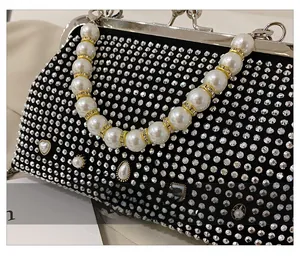 Detailed close-up of a black rhinestone evening bag with pearl handle and metal clasp