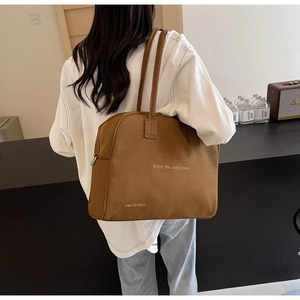 Brown canvas tote bag detail showing Enjoy Life and Travel lettering in a cafe setting