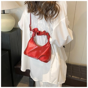 Detail of red shiny PU leather bag with ruched handle and embossed logo on the surface