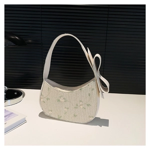 Sac hobo blanc avec panneau tissé floral et grand nœud décoratif sur la bandoulière