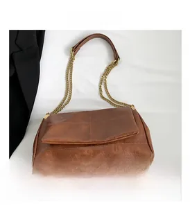 Detail of brown PU leather handbag featuring lychee texture and gold chain strap