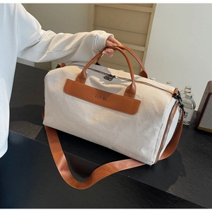 Detail of beige canvas tote bag with brown leather handles and adjustable shoulder strap