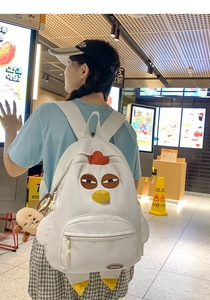 Detail of white chicken canvas backpack with 3D beak, embroidery eyes and plush bear charm