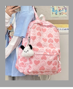 Close-up of pink nylon backpack with heart prints and cute plush puppy pendant charm