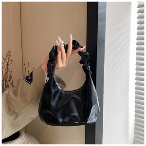 Detail view of black patent leather hobo bag with cloud pleat handle and silver zipper