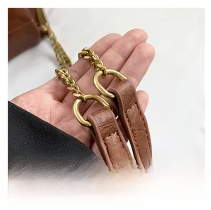 Close-up of brown litchi pattern PU leather handbag with gold metal chain handle detail
