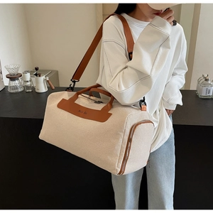 Macro detail of large canvas travel bag showing beige fabric and brown leather accents