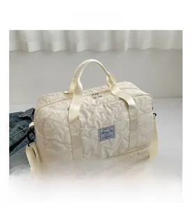 Macro view of beige star-quilted travel bag featuring a reinforced handle and bottom compartment