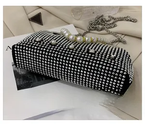 Close-up of black evening bag with silver rhinestones, large pearls and metal chain