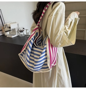 Lifestyle shot of large striped canvas hobo bag worn by model in a cozy cafe
