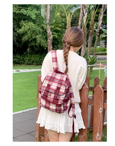 Detail of red white and blue plaid tweed backpack on model in a sunny park setting
