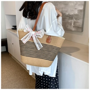 Straw tote bag with black stripes and large white lace bow with pink floral embroidery
