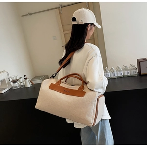 Detail of a large canvas travel bag with brown leather handles and side zipper pocket