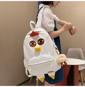 Detail of cute cartoon chicken backpack made of white canvas with plush cookie charm pendant