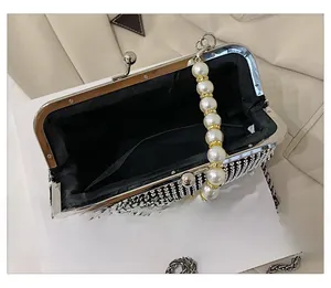Detail view of rhinestone evening clutch with pearl handle, chain strap and black lining
