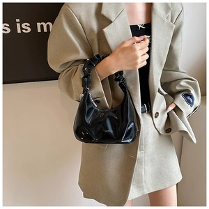 Detail showing the glossy black PU leather surface and stylish pleated handle of the handbag