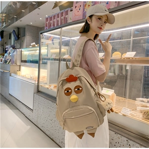 Detail of beige nylon backpack with cute cartoon chicken design and plush charm