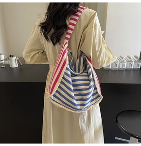 Detailed back view of a large blue and pink striped canvas hobo bag on a model