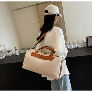 Spacious beige canvas crossbody travel bag with brown leather accents on a model