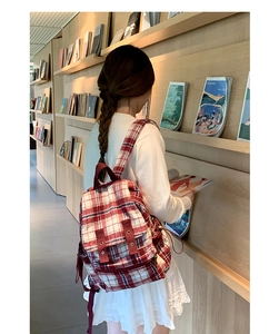 Detail of red and white checkered tweed backpack styled in a modern library setting