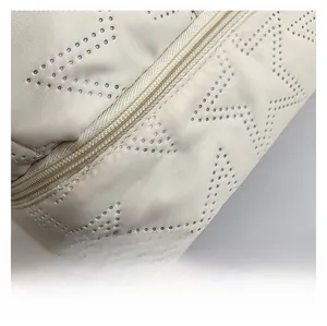 Macro shot of breathable perforated fabric and neat zipper stitching on a beige bag