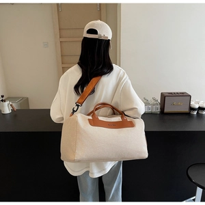 Detail view of oatmeal canvas tote bag with brown leather trim and wide crossbody strap