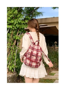 Outdoor shot of a red and white checkered fabric backpack with flap design on a model