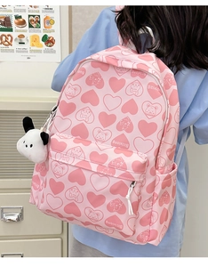 Close-up of pink nylon backpack with heart bear prints and a plush dog pendant