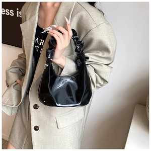 Detailed close-up of glossy black PU leather bag featuring unique ruffled handle design