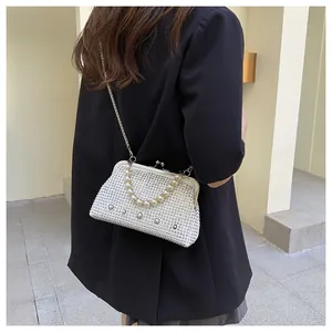 Detail of white rhinestone evening bag with pearl handle and metal frame closure