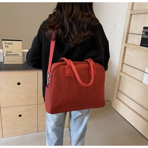 Rear view of model wearing a large brown canvas tote bag with adjustable wide strap