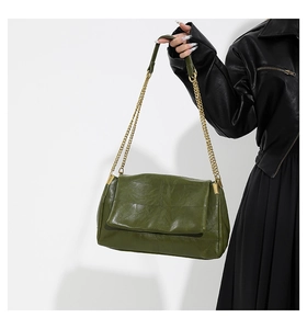 Detail of dark green PU leather handbag with square stitching and gold chain strap