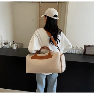 Detail of beige canvas crossbody bag with brown leather trim and Moco Bag logo