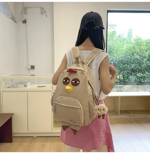 Close-up of a cute beige cartoon chicken nylon backpack with red comb and plush pendant