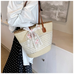 Detail of summer straw tote bag with lace bow, rose embroidery and brown leather straps