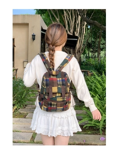 Detailed view of the vintage plaid tweed backpack with decorative brown straps on person