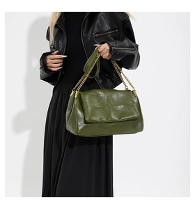Close-up of olive green PU leather shoulder bag with gold chain strap on a model